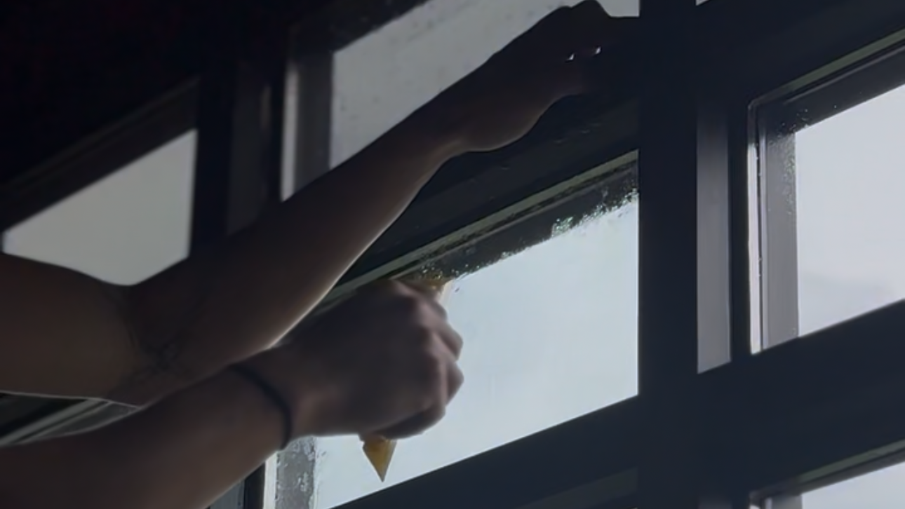 Person applying commercial window film to window with a squeegee