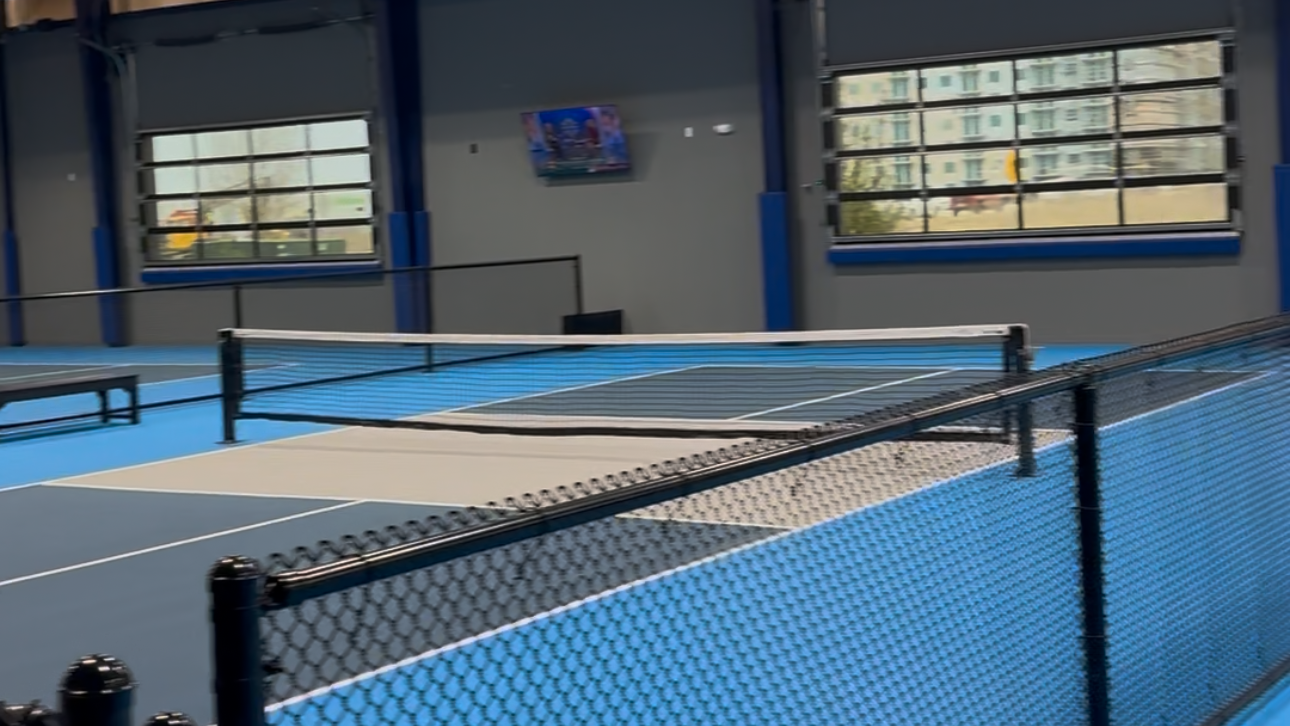 Indoor pickleball sports facility our team tinted with a blue court and black net.