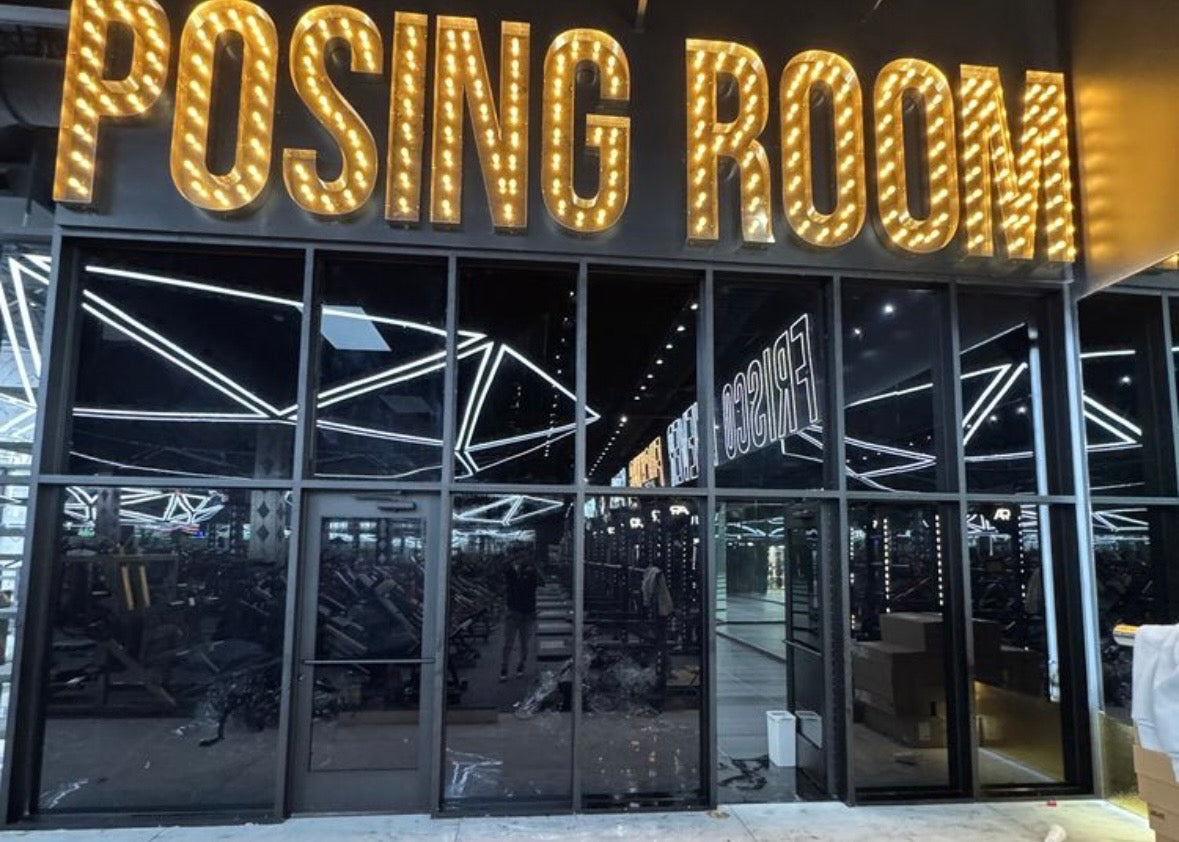Flat glass tint job for Absolute Recomp in Frisco. Lit up 'Posing Room' sign illuminated at night.